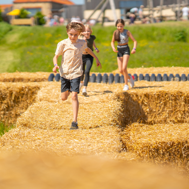 Little boy running on straw bales